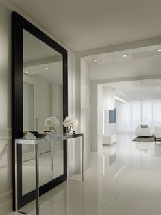 a white room with a mirror and flowers on the table in front of it's door