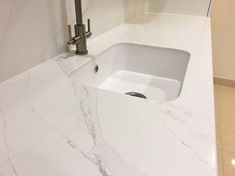 a white sink sitting under a faucet on top of a marble countertop