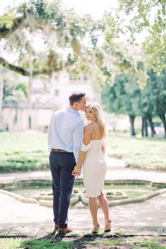 an engaged couple standing in front of a tree