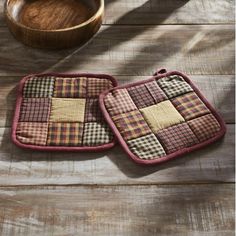 two pot holders on a wooden table with a bowl in the background