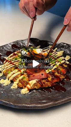 a person cutting up food with chopsticks on top of a metal platter