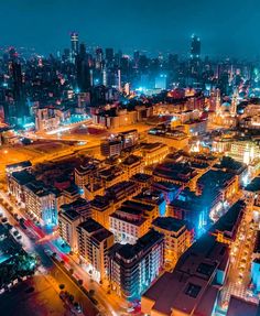 an aerial view of a city at night with lots of lights and buildings in the foreground