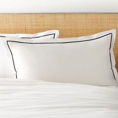 a bed with white sheets and black trimmings on the headboard is shown