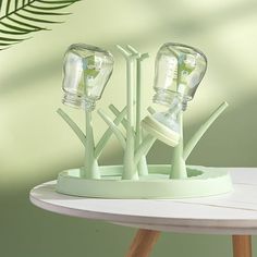 three glass vases sitting on top of a white table next to a palm leaf