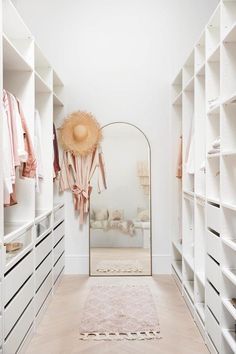 a walk in closet with white shelving and drawers