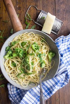 a bowl of pasta with broccoli and parmesan cheese on the side