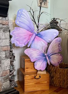 two purple butterflies sitting on top of wooden boxes in front of a fire place with a basket