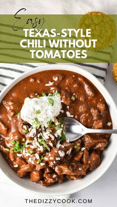 a white bowl filled with chili and topped with sour cream