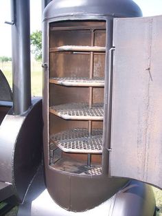 an old fashioned stove is sitting outside in the grass and has shelves for cooking food