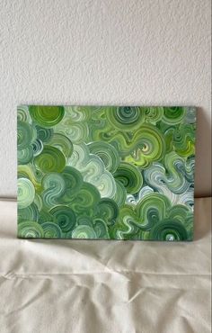 a green and white painting sitting on top of a bed