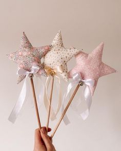 a hand holding three star wands with bows