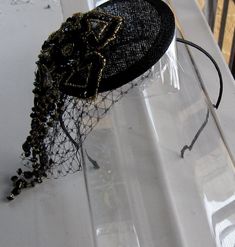 This Black and Gold Beaded Flower Sinamay Fascinator Hat with Veil and Satin Headband is a beautiful accessory for weddings, parties, cocktail, evening, and other special occasions. It is elegant, sparkling, stylish, and super chic! The perfect Fall/Winter piece that will definitely add a special touch to your outfit!! ** Black Sinamay Base is 10 cm. I only accept PayPal and ship all orders within 24 hours via USPS. Feel free to send me a convo with any questions. Thank you for visiting Hettie Hair Accessories! Gatsby Style Evening Fascinator Headband, Evening Gatsby Style Fascinator Headband, Adjustable Fascinator With Structured Crown For Party, Vintage Evening Fascinator Headband, Adjustable Round Crown Fascinator For Parties, Evening Hat Shaped Headband For Royal Ascot, Elegant Handmade Headpiece With Structured Crown, Adjustable Vintage Fascinator For Party, Gatsby Style Headband Hat For Evening