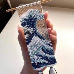 a woman holding up a phone case with an image of a wave on it