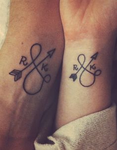 two people with matching tattoos on their arms and wrist, both holding hands in the same direction