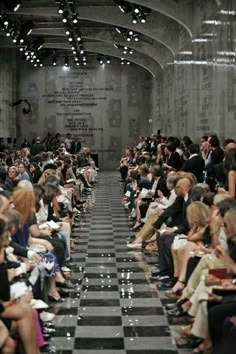 a crowd of people sitting on top of a checkered floor in front of a wall