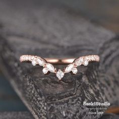 a rose gold wedding band with three diamonds on the top, and two leaves in the middle