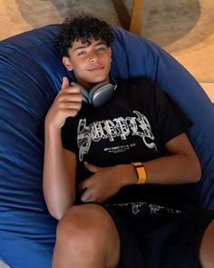 a boy sitting on a bean bag chair talking on the phone