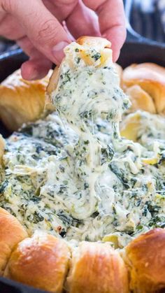 spinach dip being scooped from a skillet with croissants in it