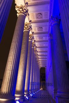 columns lit up with blue lights in the night time sky and on to them are white pillars