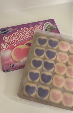 a box of heart shaped cookies next to a package of candy hearts on a table