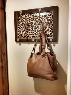 two purses are hanging on a wall with leopard print and metal hooks attached to it