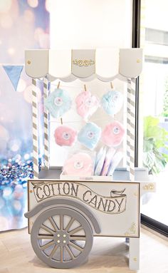 a cotton candy cart with pink, blue and white lollipops on it