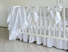 a crib with white bedding and bows on it