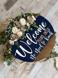 a wooden sign with flowers and greenery on it