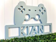 a metal sign with a video game controller on it's side and the words kian written in large letters