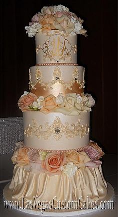 a three tiered wedding cake with flowers on it's side and the top layer is gold