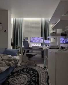 a bedroom with a bed, desk and computer monitor in the corner next to a window