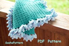 a blue and white crocheted blanket sitting on top of a wooden fence