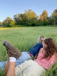 two people laying in the grass with their feet up