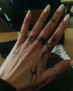 a woman's hand with tattoos on it and a ring in her left hand