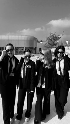 a group of people standing next to each other in front of a building with sunglasses on