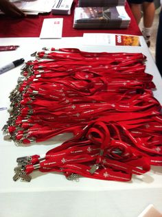 several red cords are lined up on a white table with a black pen and scissors