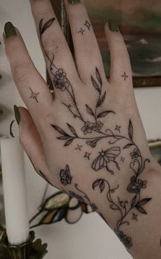 a woman's hand with tattoos on it and flowers in the middle of her arm