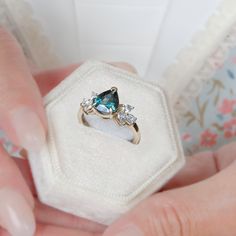 a woman's hand holding an engagement ring with blue and white stones