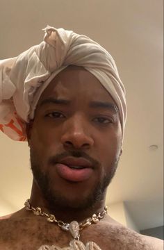 a man with a turban on his head wearing a gold necklace and a white bandana