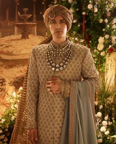 Infused with centuries-old artistry, EVARA’s muted sikandari blue brocade sherwani features intricate nakshi embroidery and glistening metallic sequins. The ensemble, completed with a kurta churidar, a richly embroidered silk palla, and a muted brown striped chanderi safa, offers a sophisticated blend of tradition and modern grace. Groom Wedding Jewellery, Men's Wedding Outfit, Sherwani Groom, Indian Groom Wear, Indian Wedding Outfit, Mens Wedding Attire, Manish Malhotra, Indian Groom