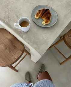 a person sitting at a table with a plate of croissants on it