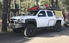 a white truck parked next to a forest filled with trees