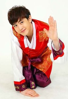 a young man dressed in traditional chinese clothing poses for the camera with his hand up