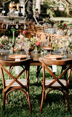 an outdoor table set up with flowers and place settings