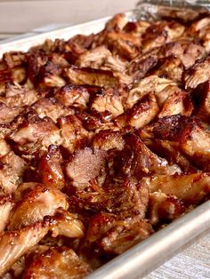 a pan filled with meat sitting on top of a wooden table