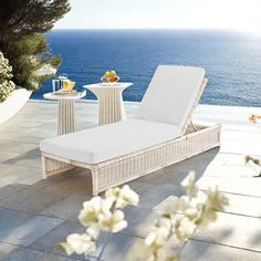 a white chaise lounger sitting on top of a patio next to the ocean