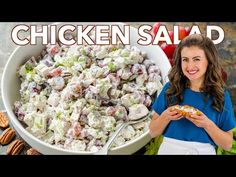 a woman holding a plate with chicken salad in it next to a bowl full of nuts