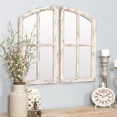 an old white window frame on a mantle with candles and vases next to it