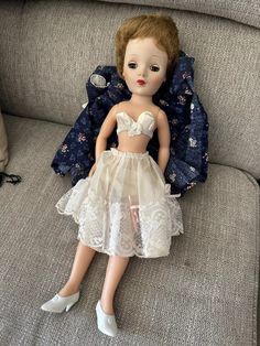 a doll is sitting on a couch wearing a dress