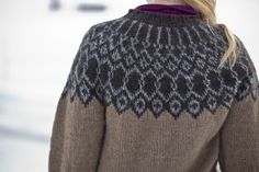 a woman with blonde hair wearing a brown and black sweater in the snow, back view